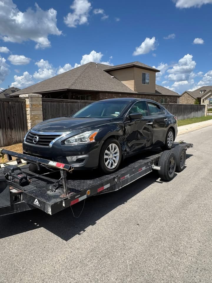 Black Nissan Altima loaded on a flatbed tow trailer in San Antonio