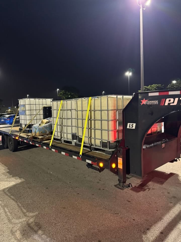 Gooseneck flatbed loaded with IBC totes for an after-hours material delivery