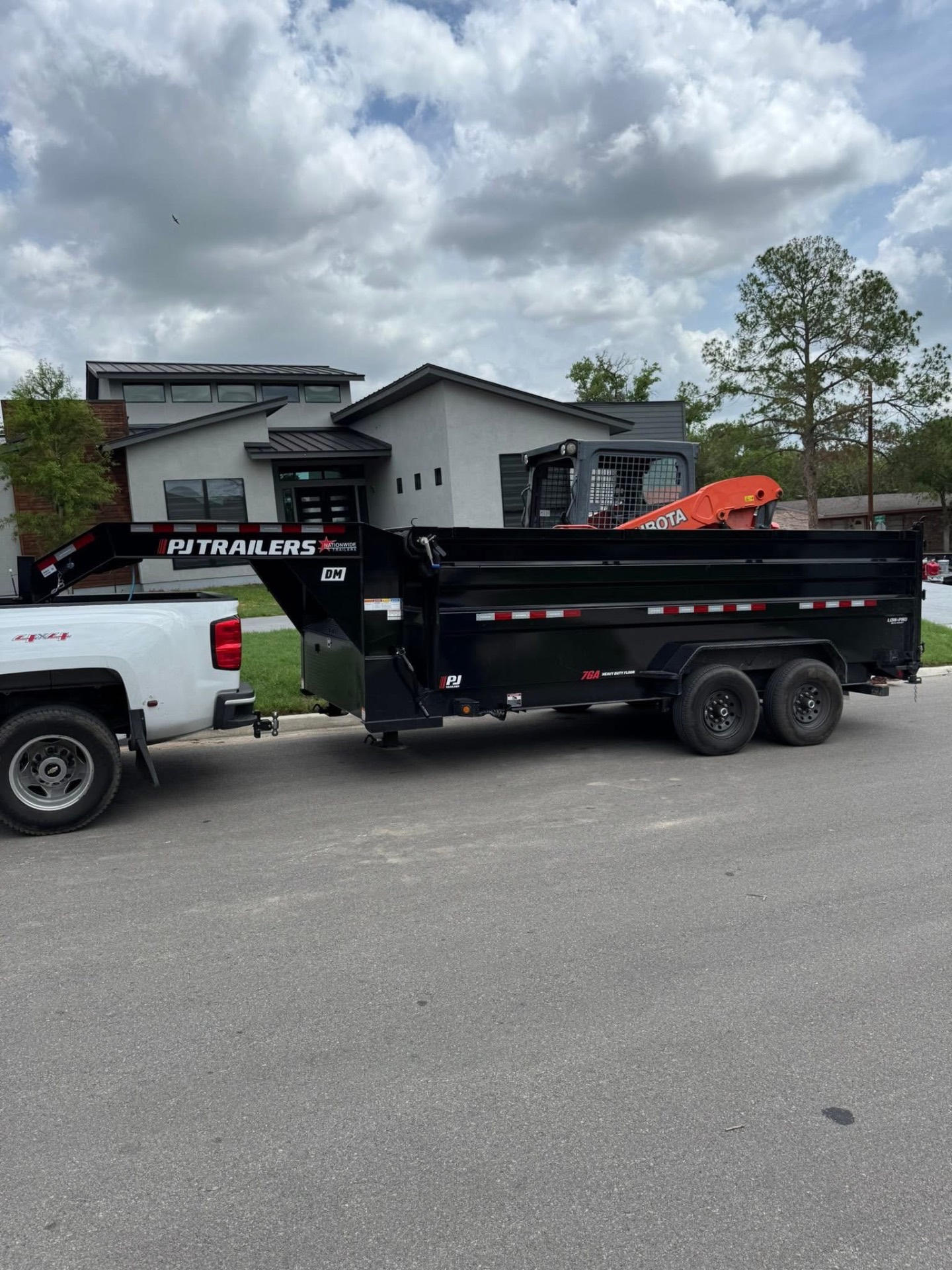PJ gooseneck dump trailer hauling a Kubota skid steer in San Antonio